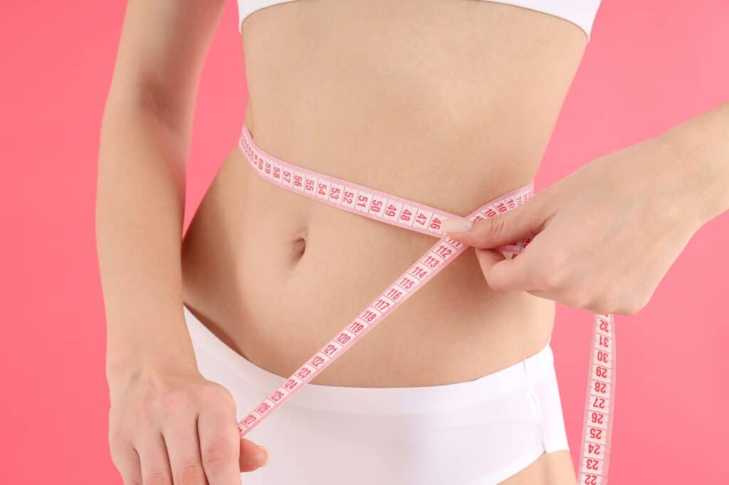 Concept of weight loss with young slim woman on pink background